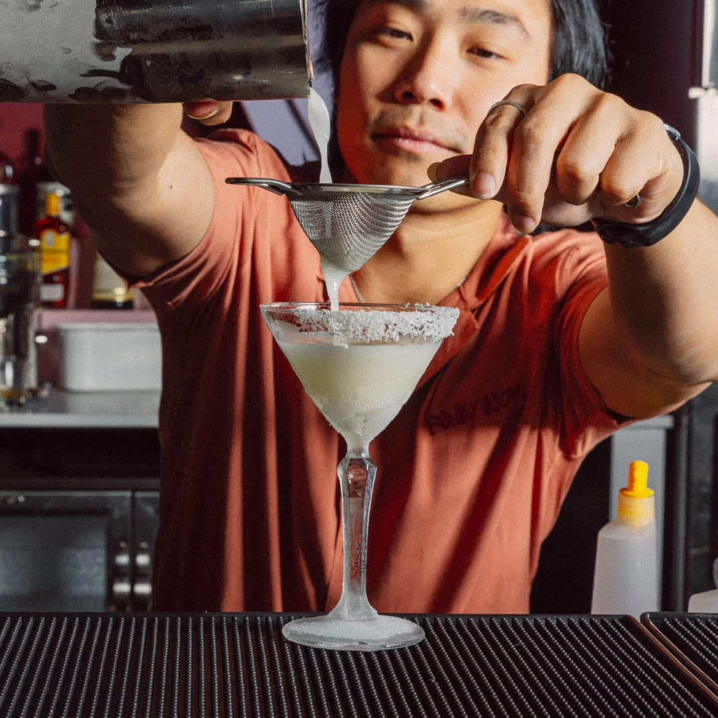 A bartender straining a martini