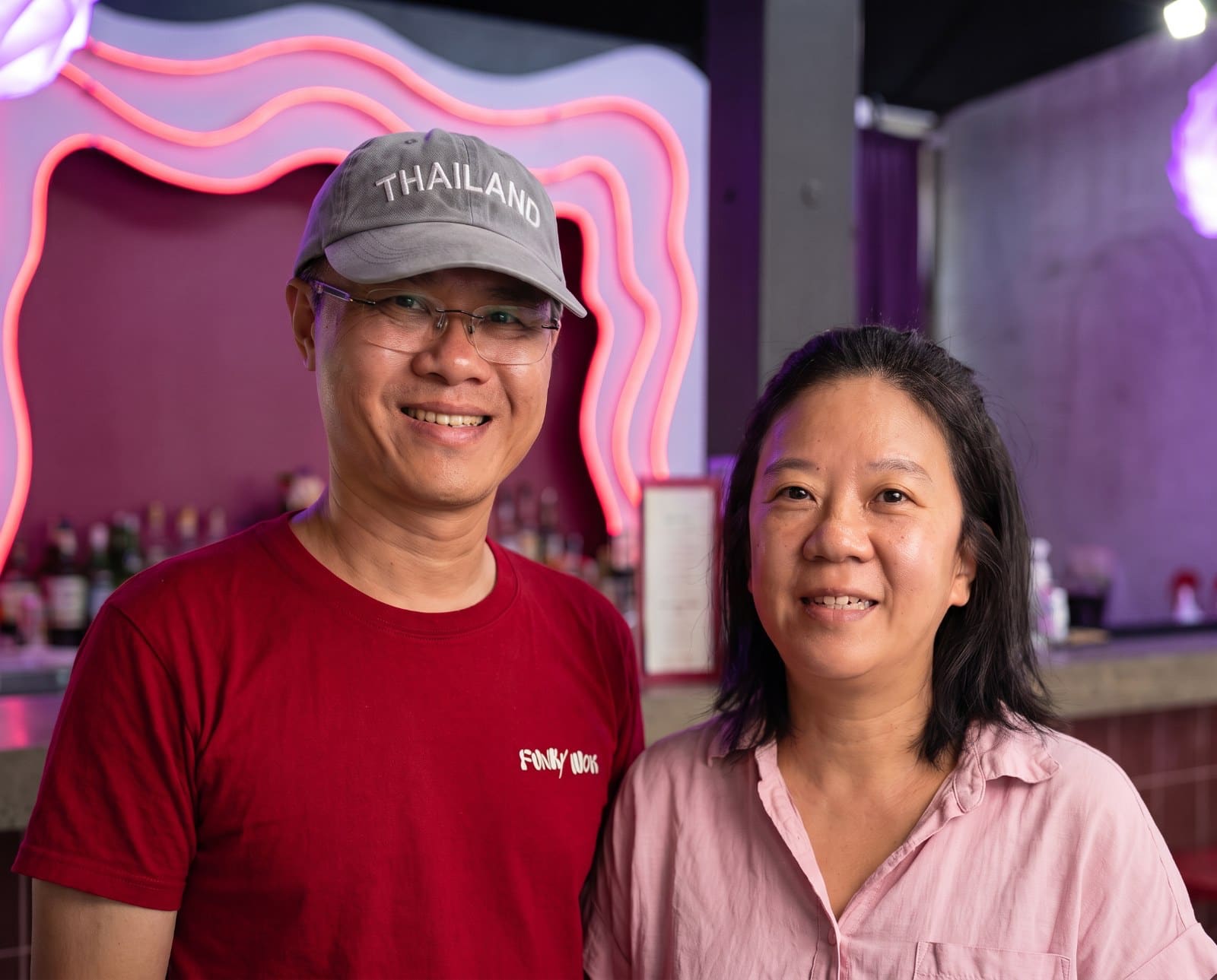 Oat and Pui, the owners of Funky Wok, in front of the pink neon wall